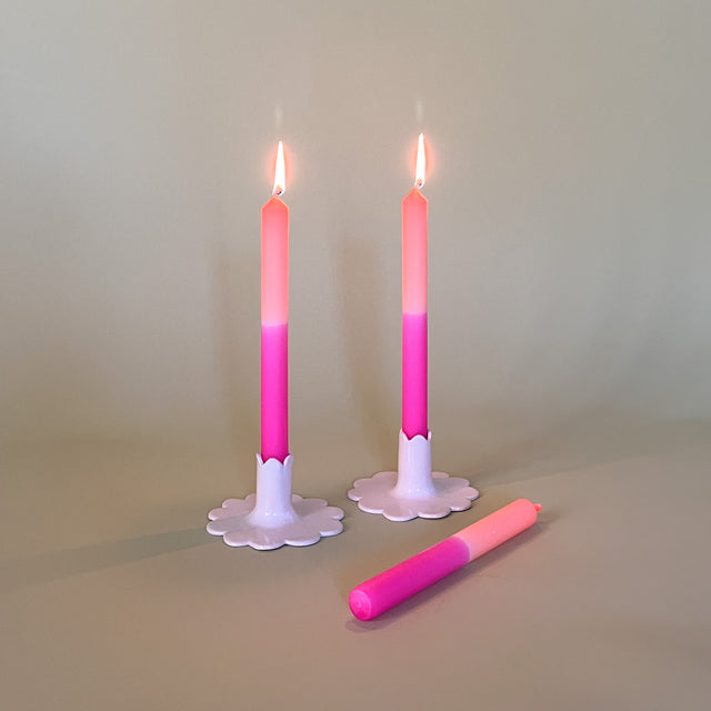 pink and orange taper candles in white scalloped candle holders