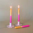 pink and yellow taper candles in white scalloped candle holders