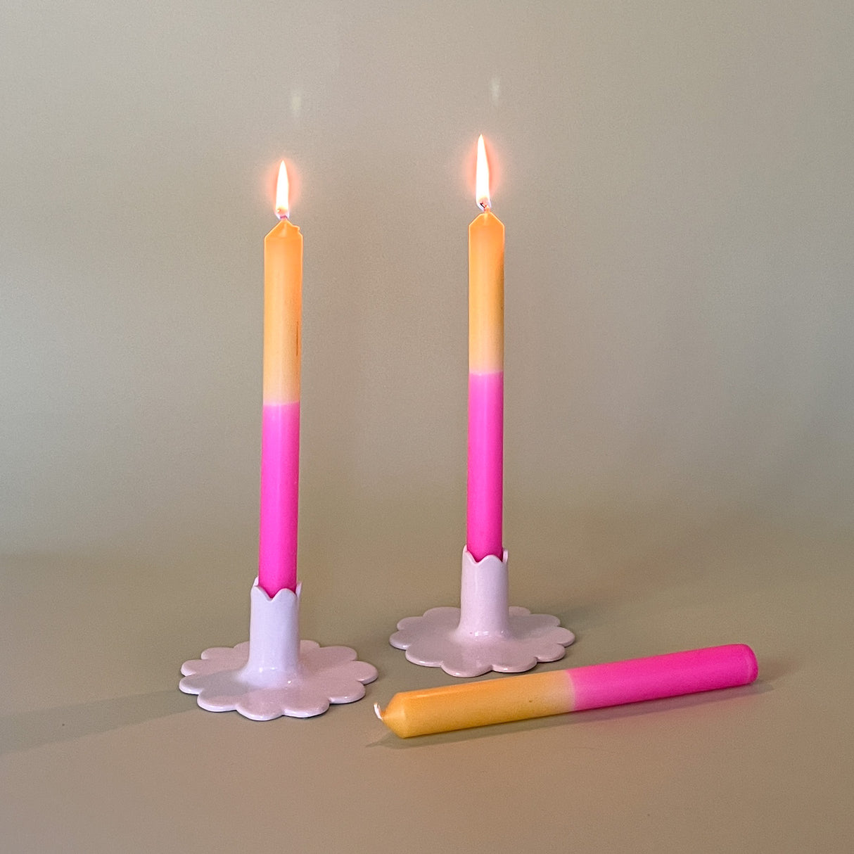 pink and yellow taper candles in white scalloped candle holders