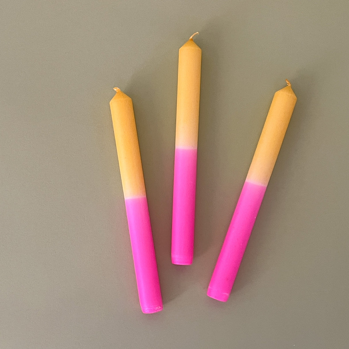 three pink and yellow taper candles