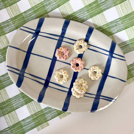 An oval shaped ceramic blue and white platter featuring a blue plaid pattern on white background. 