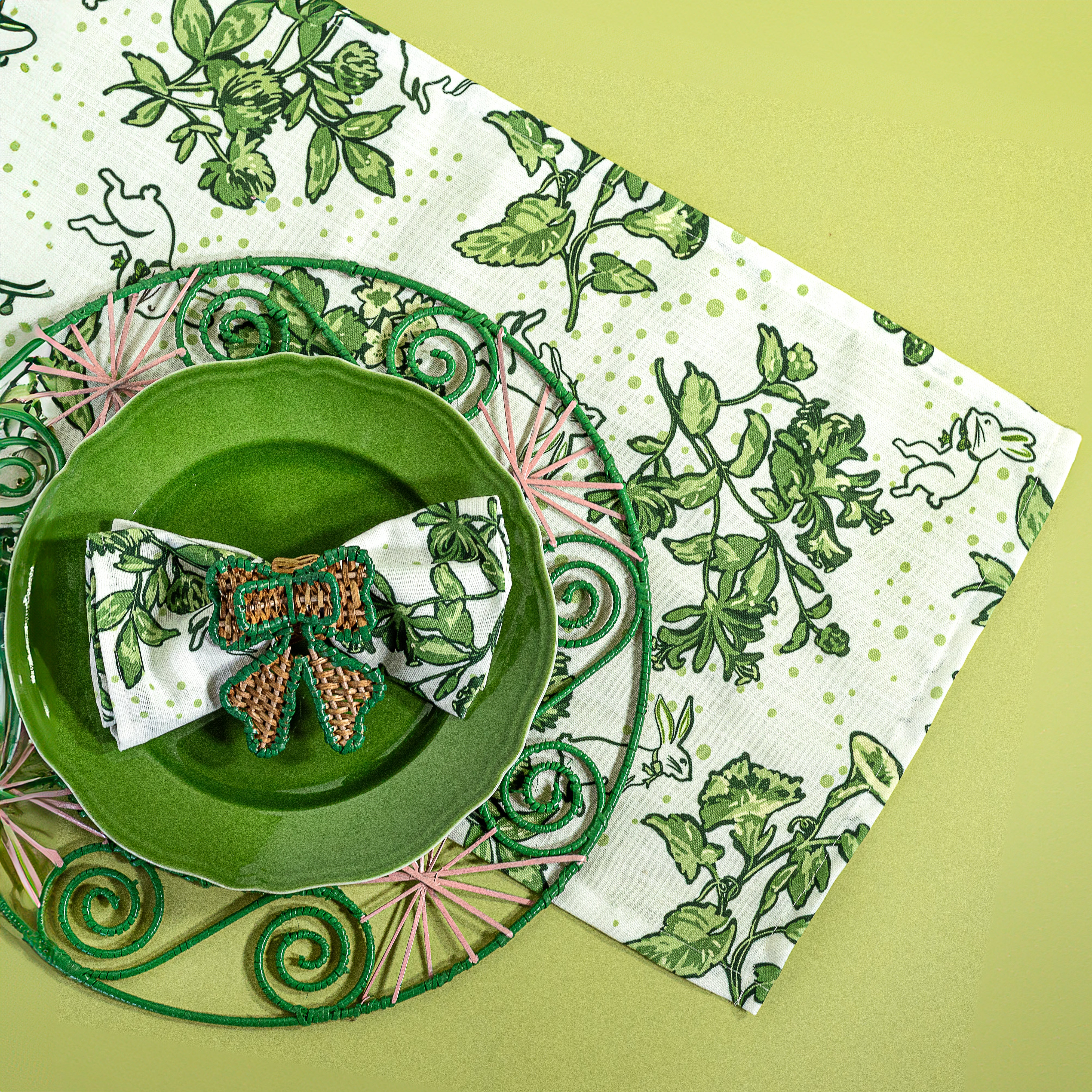 a springtime strawberry print fabric easter table runners in green with a green plate and round rattan charger