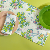 a springtime strawberry print fabric easter table runner in green with two plates on it
