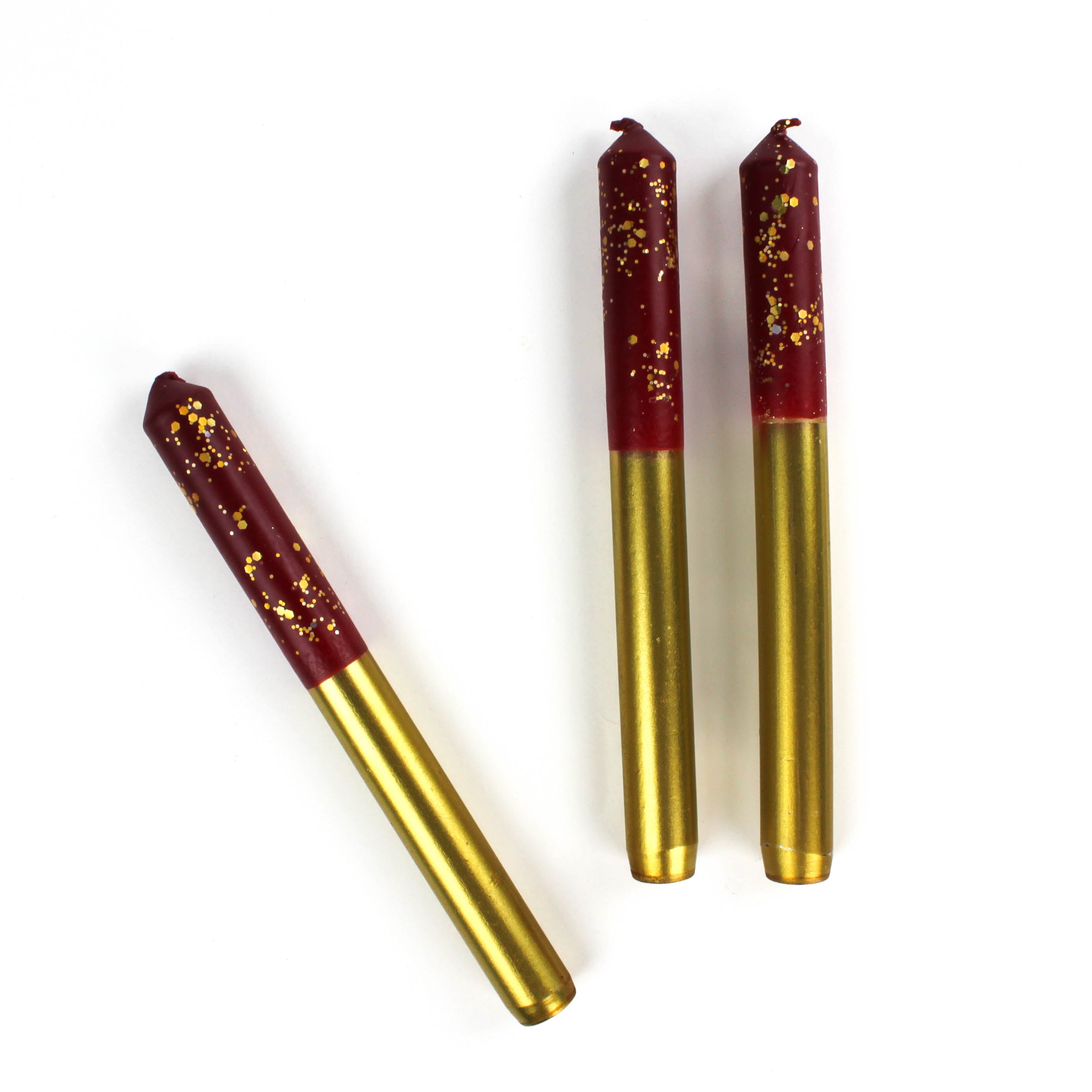 3 plum pudding gold taper candles lying in a white background
