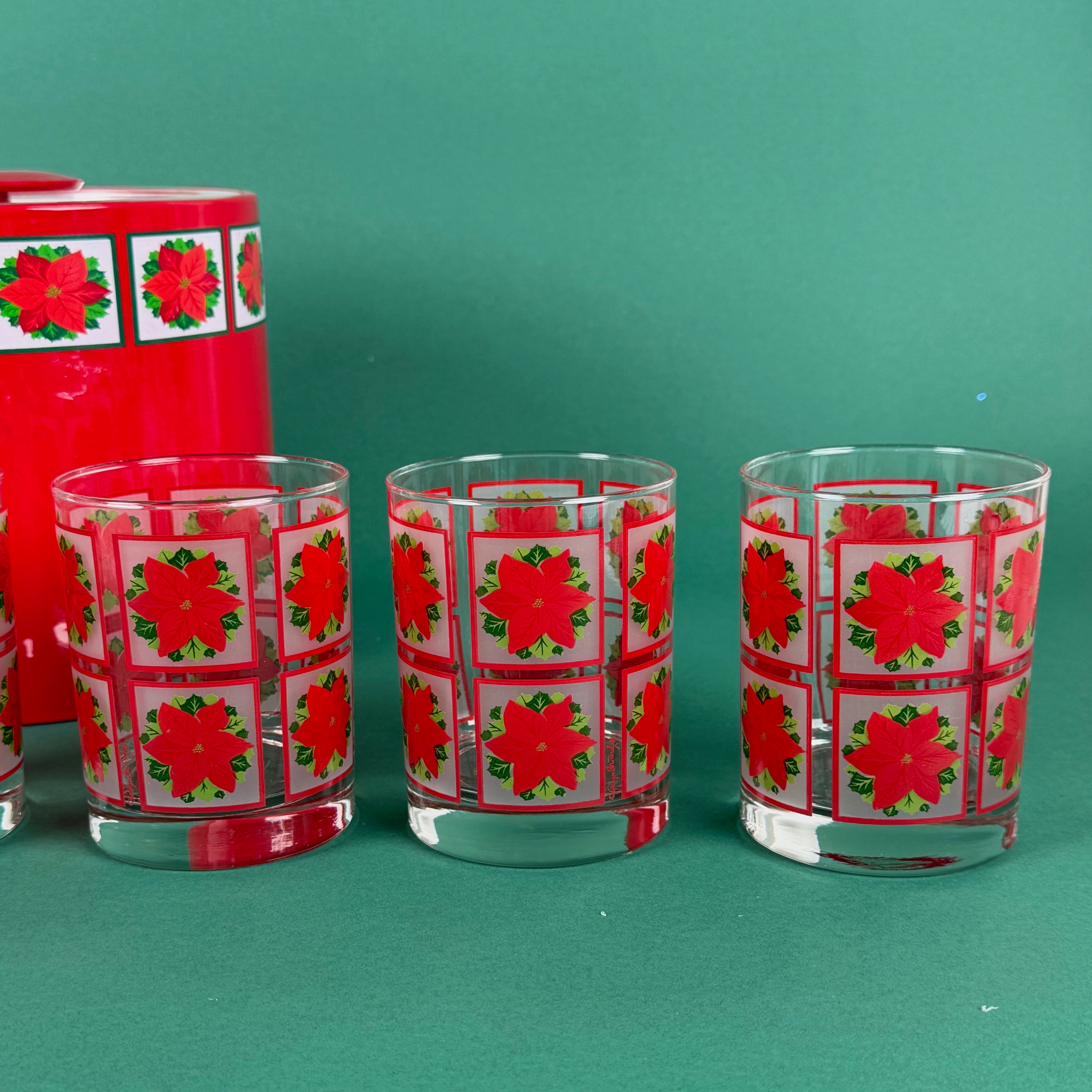 3 Clear drinking glass decorated with red poinsettia flower squares on a green background