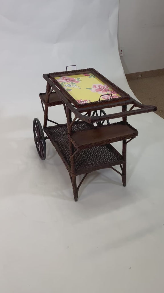 A brown vintage bar cart with a removable yellow floral tray
