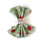 a green christmas napkins with pugs, christmas trees and candy cane motifs inside a santa napkin on a white background