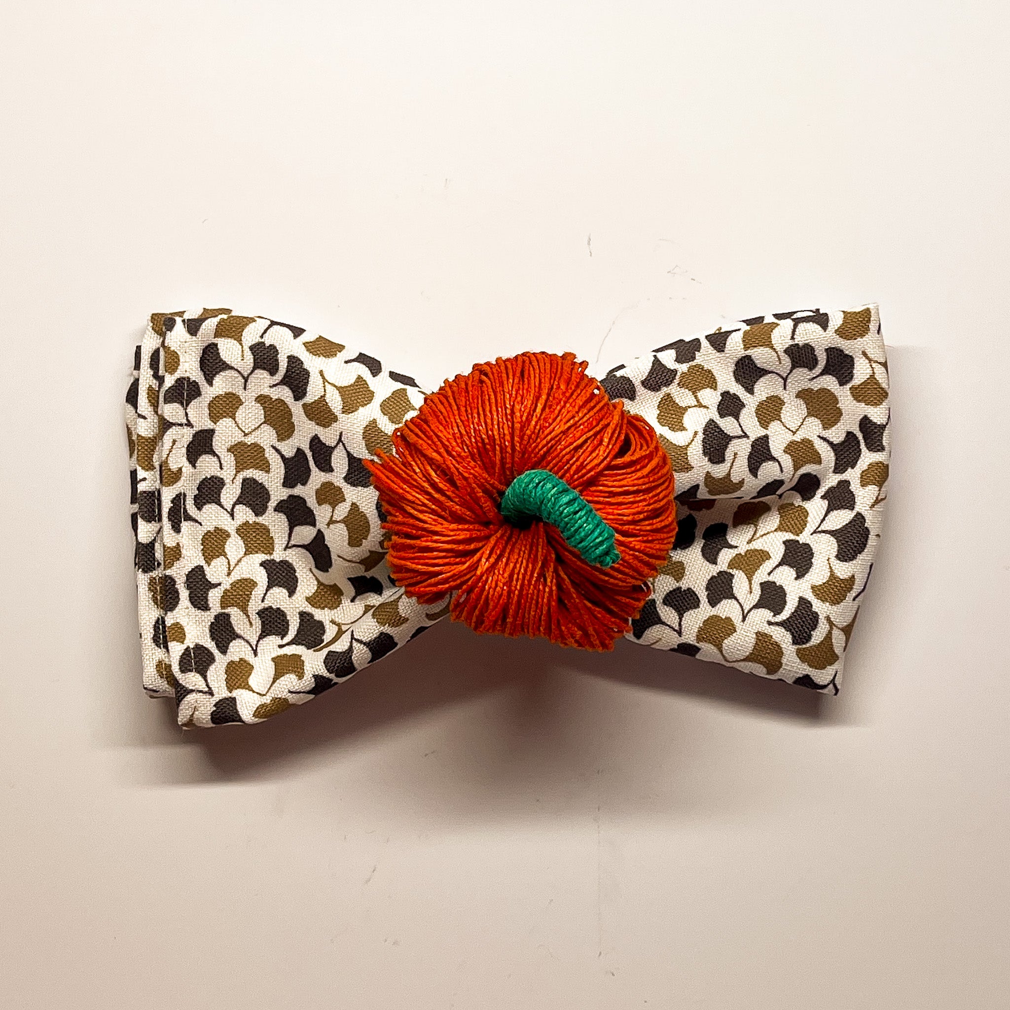 an orange pumpkin napkin ring holding a brown and white napkin