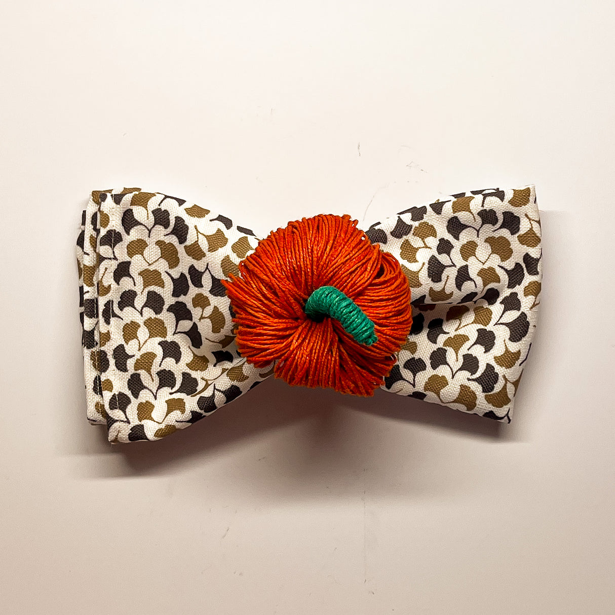 an orange pumpkin napkin ring holding a brown and white napkin