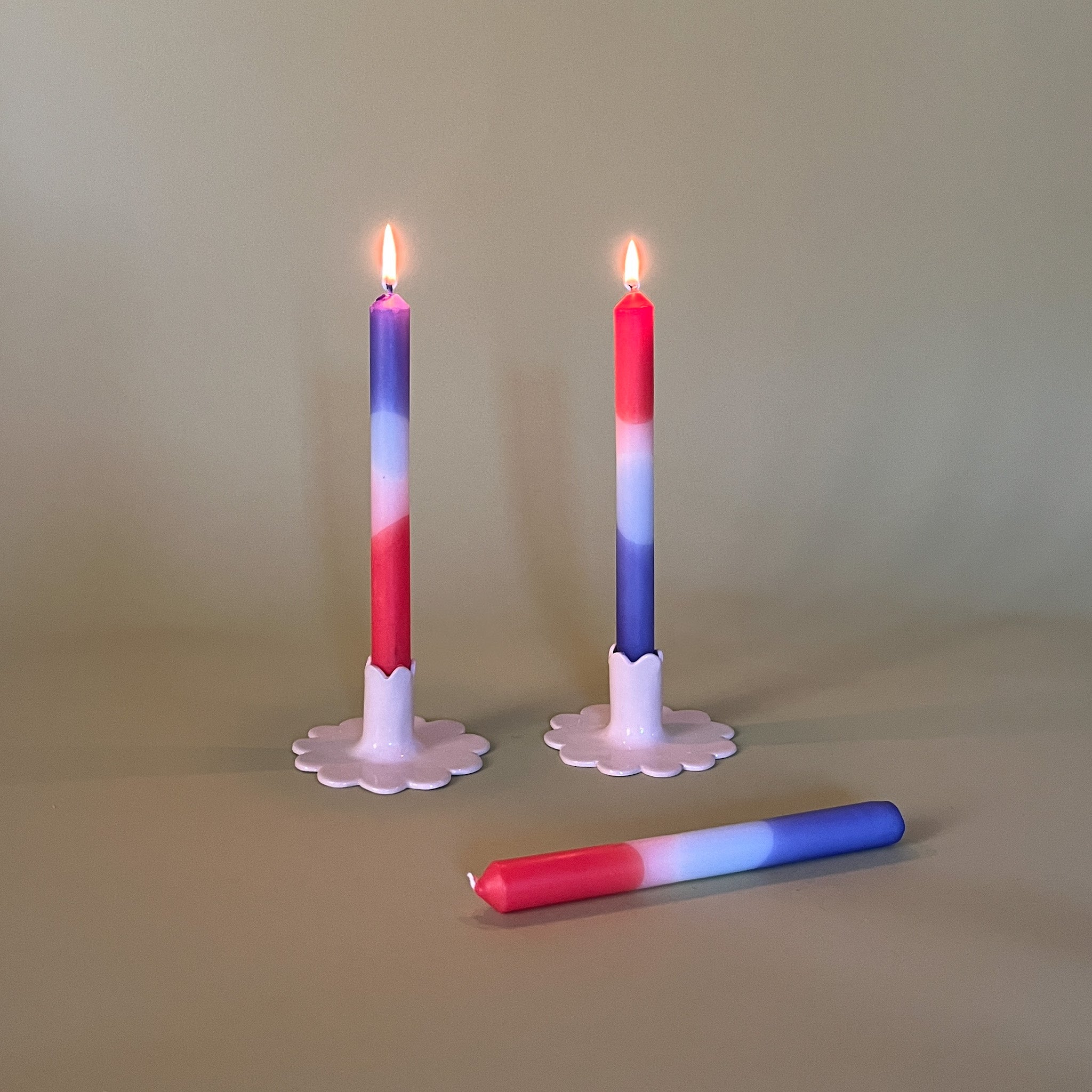 a pair of white ceramic candle holders with purple and hot pink taper candles
