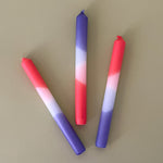 a trio of colorful taper candles in a mix of white, purple and hot pink. 