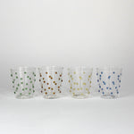 four glasses with raised dot embellishments, one green, one brown, one yellow and one blue