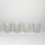four glasses with raised dot embellishments, one green, one brown, one yellow and one blue