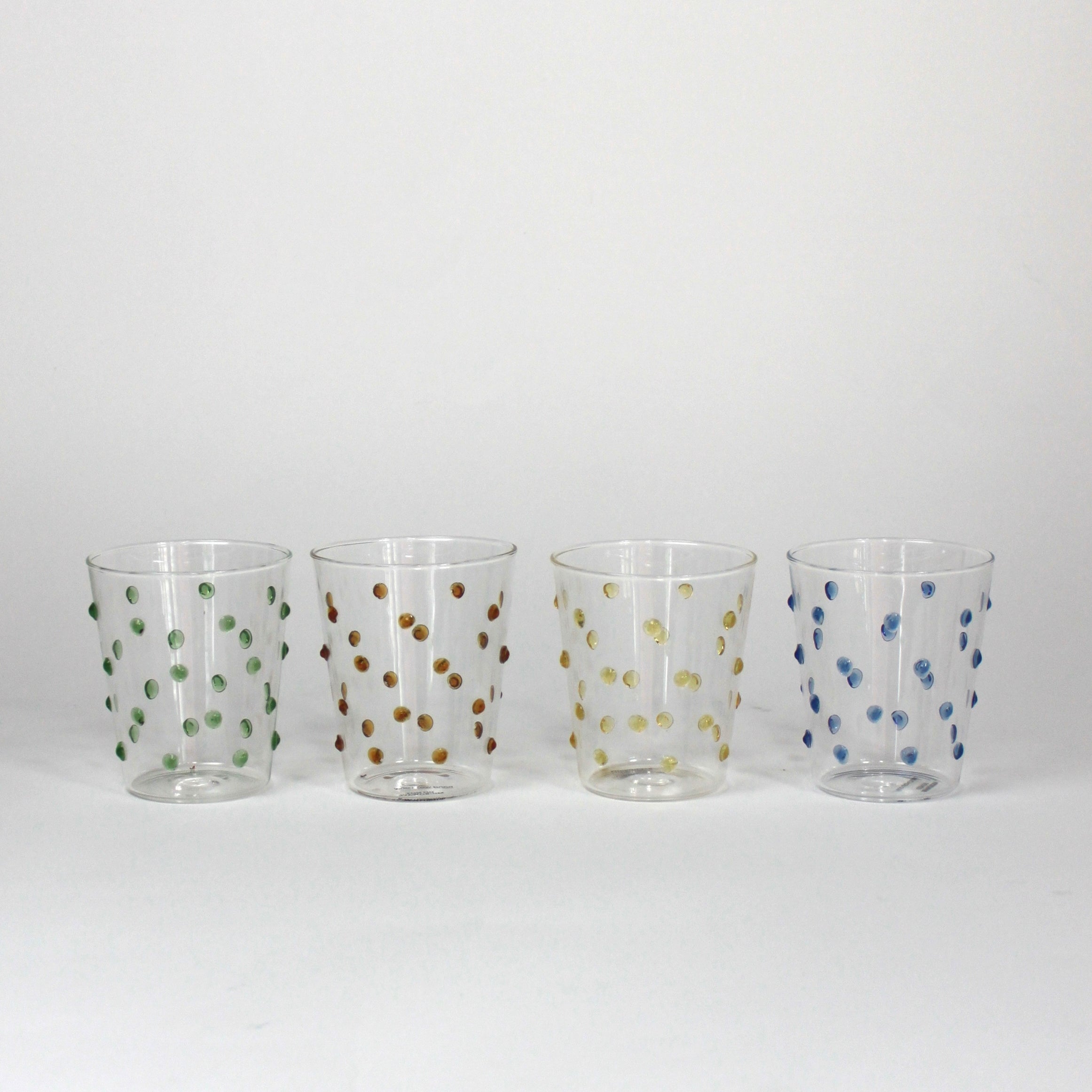 four glasses with raised dot embellishments, one green, one brown, one yellow and one blue