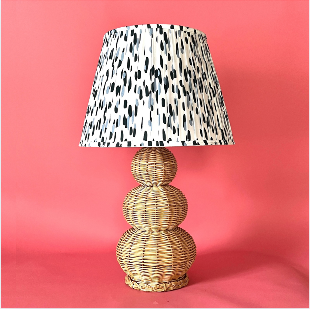 A large rattan lamp with a blue and white pleated lampshade