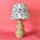 A large rattan lamp with a blue and white pleated lampshade