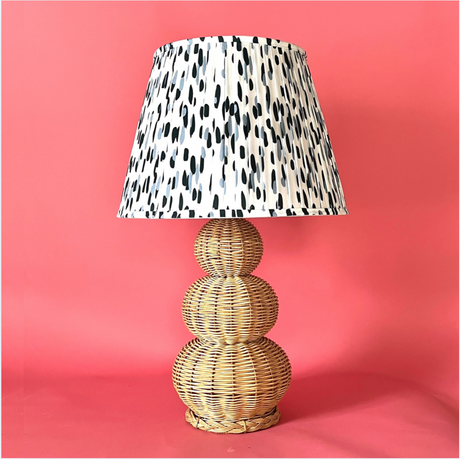 A large rattan lamp with a blue and white pleated lampshade