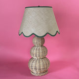 A large rattan lamp with a green trimmed scalloped lampshade from madcap cottage