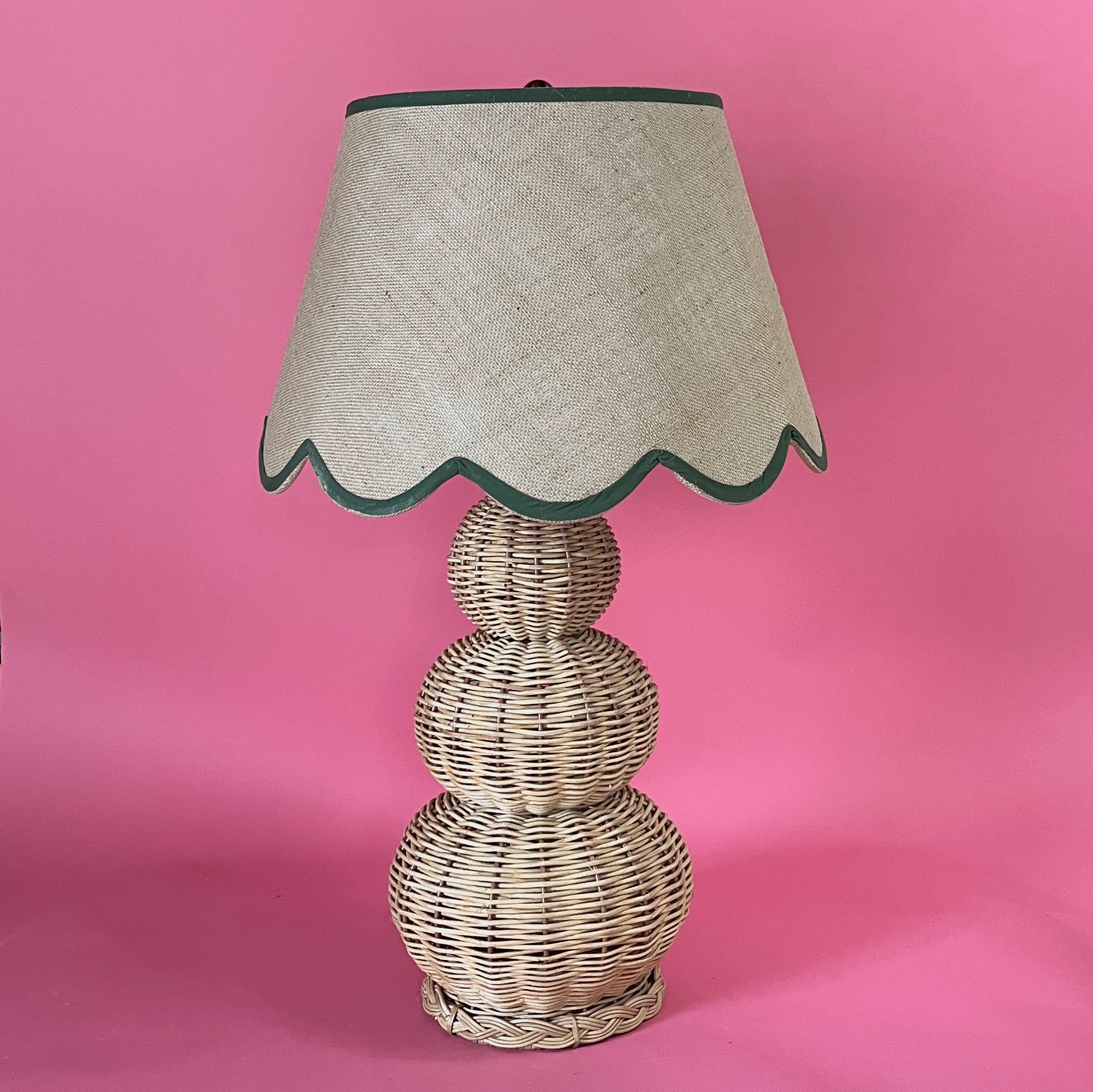 A large rattan lamp with a green trimmed scalloped lampshade from madcap cottage
