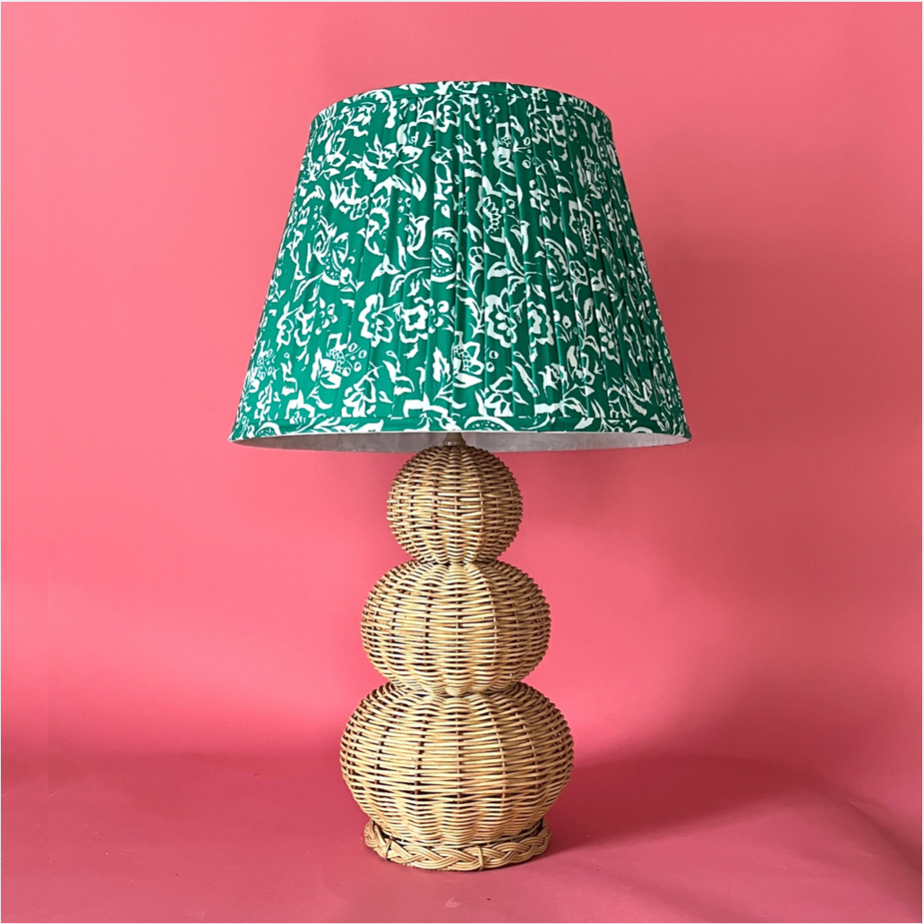 A large rattan lamp with a green floral pleated lampshade from madcap cottage