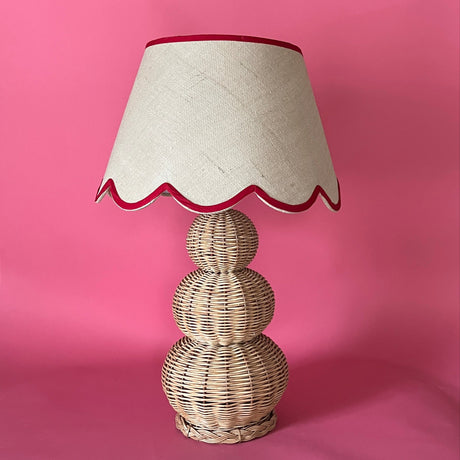 A large rattan lamp with a red trimmed scalloped lampshade from madcap cottage