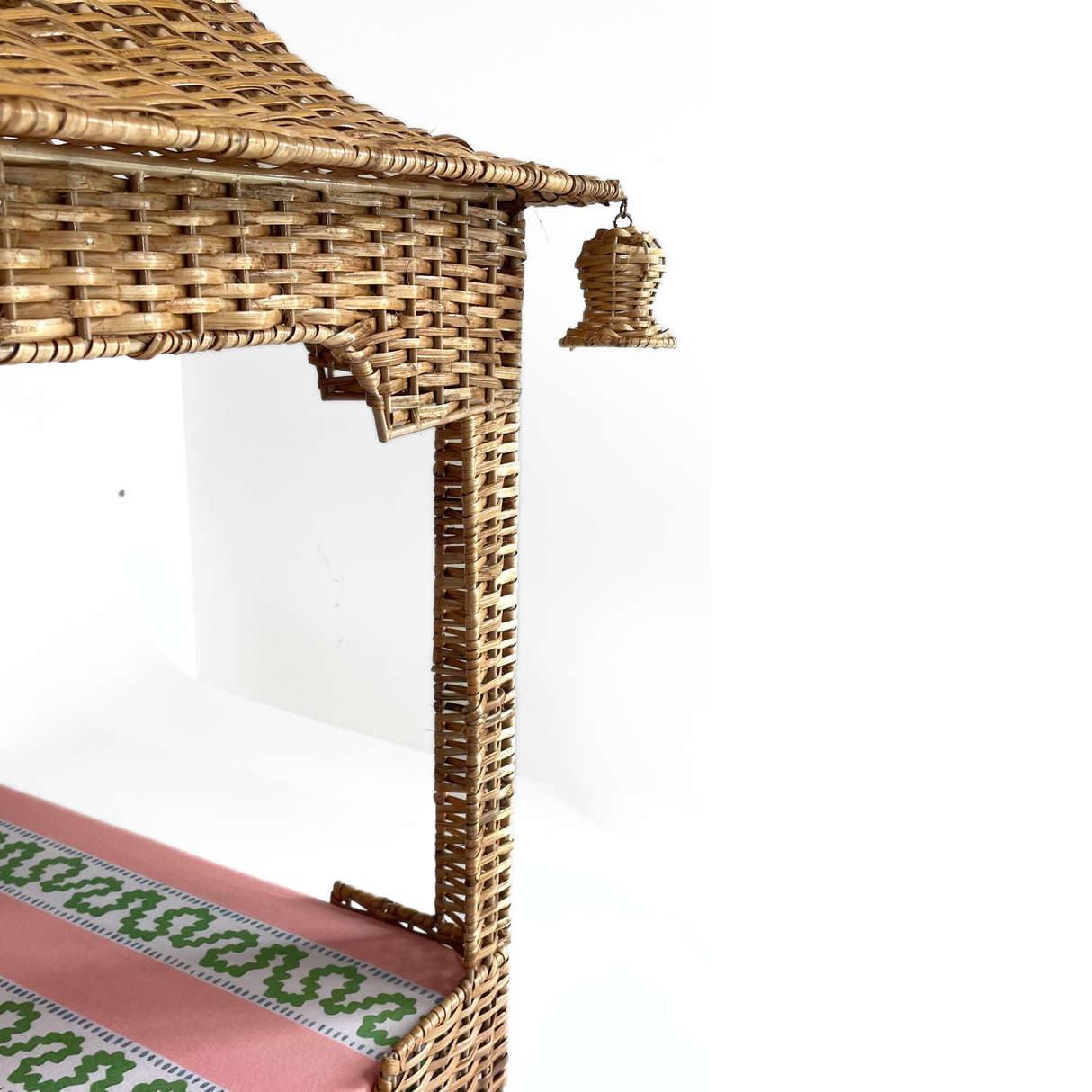 a rattan pagoda dog bed with a green pink and white striped mattress from madcap cottage