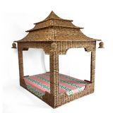 a rattan pagoda dog bed with a green pink and white striped mattress from madcap cottage