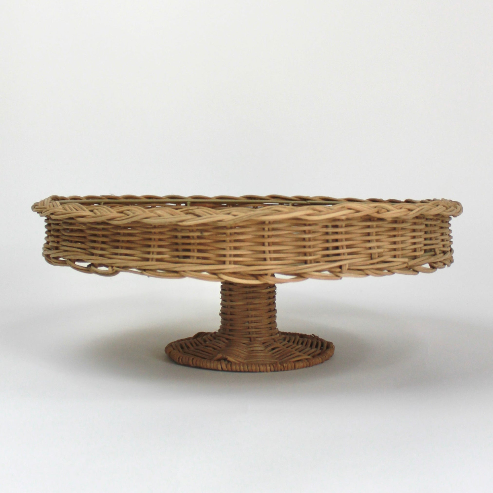 A brown rattan pedestal bowl from madcap cottage