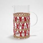 a glass pitcher wrapped in red and beige rattan