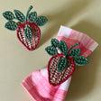 pair of strawberry rattan napkin rings with one on a pink gingham napkin