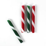 Set of red, green, and white striped christmas taper candles on a white background