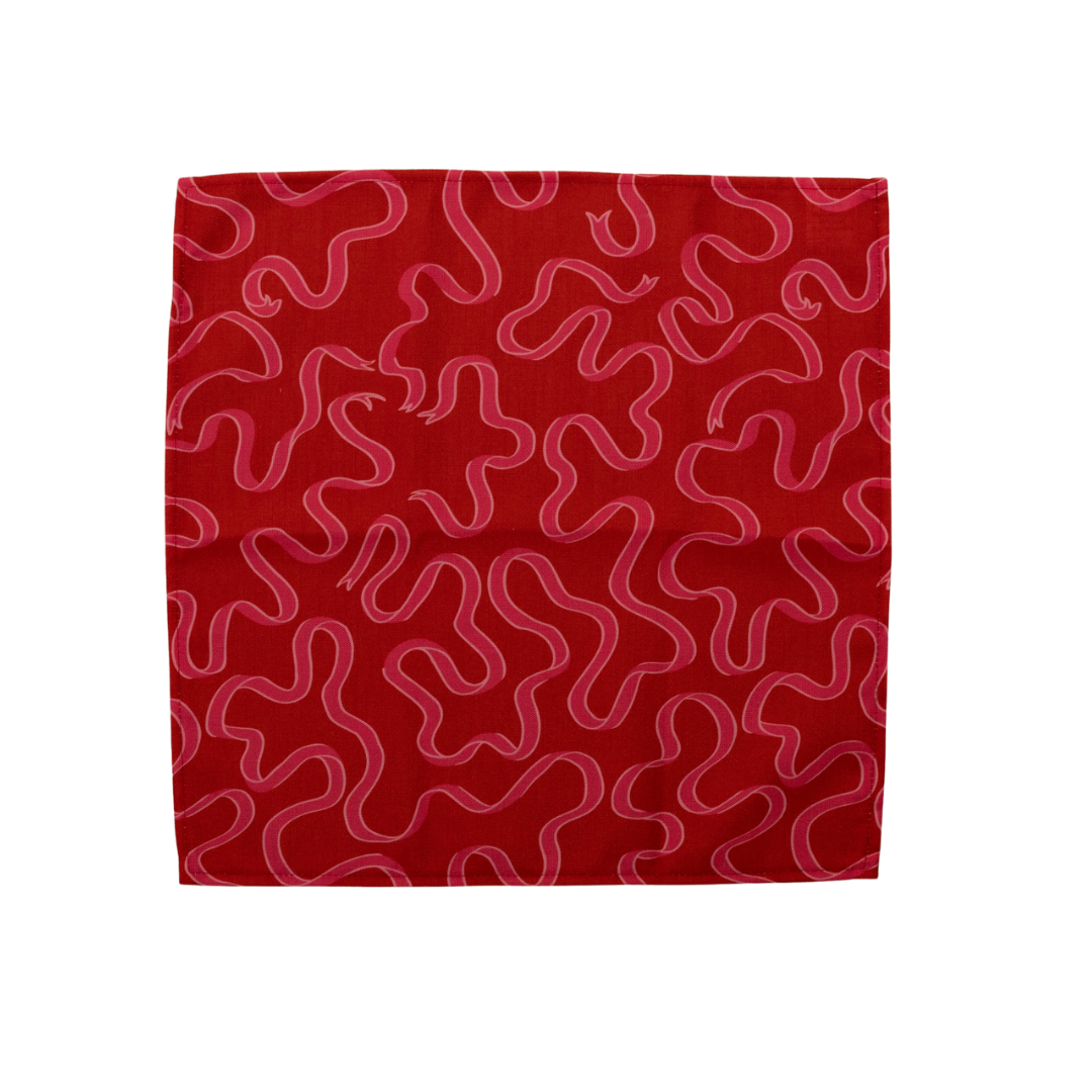 Pin ribbons patterned on a deep red cloth dinner napkin shown open on a white background