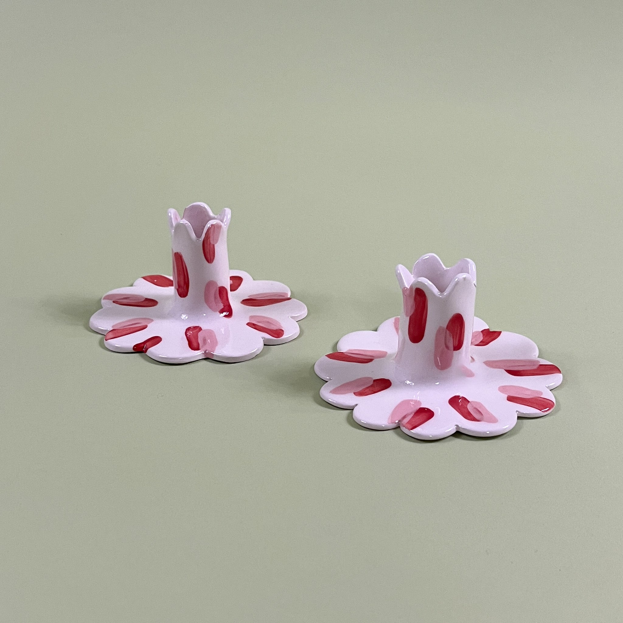 Pair of red and white scalloped ceramic candle holders with scalloped edges and a red and pink Club House pattern