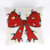 Hooked wool Christmas pillow featuring a square white design with a large red Christmas bow wrapped in multicolored holiday string lights.