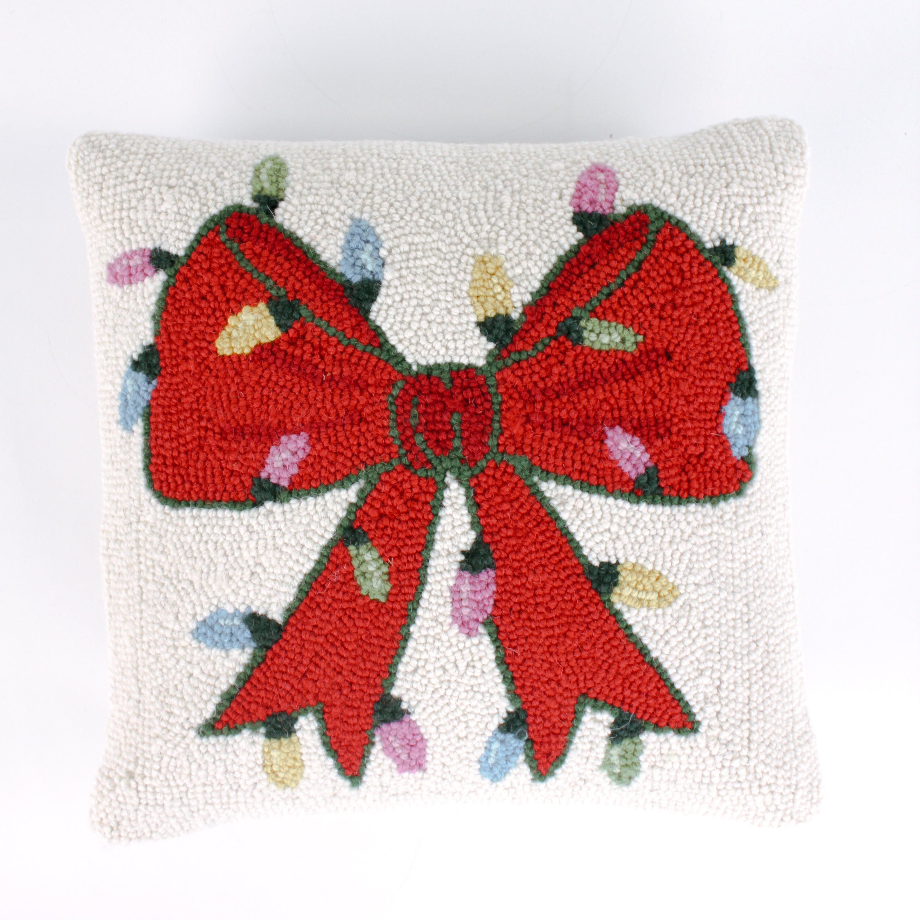 Hooked wool Christmas pillow featuring a square white design with a large red Christmas bow wrapped in multicolored holiday string lights.