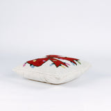 side of a Hooked wool Christmas pillow featuring a square white design with a large red Christmas bow wrapped in multicolored holiday string lights.