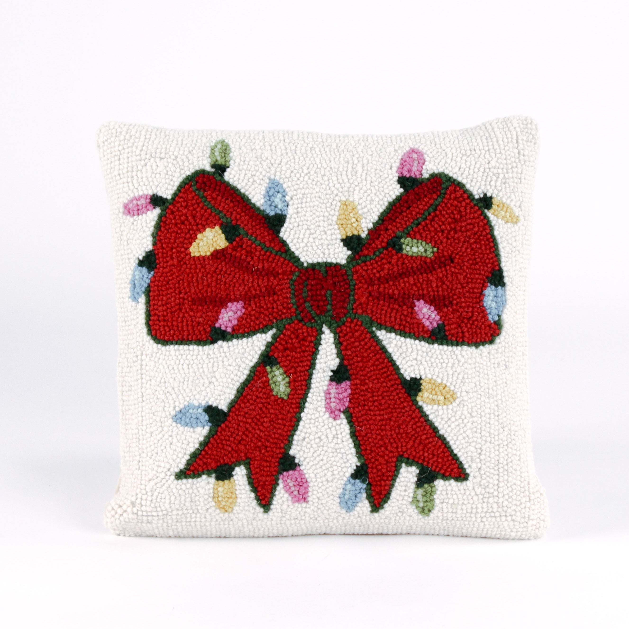 Hooked wool Christmas pillow featuring a square white design with a large red Christmas bow wrapped in multicolored holiday string lights.