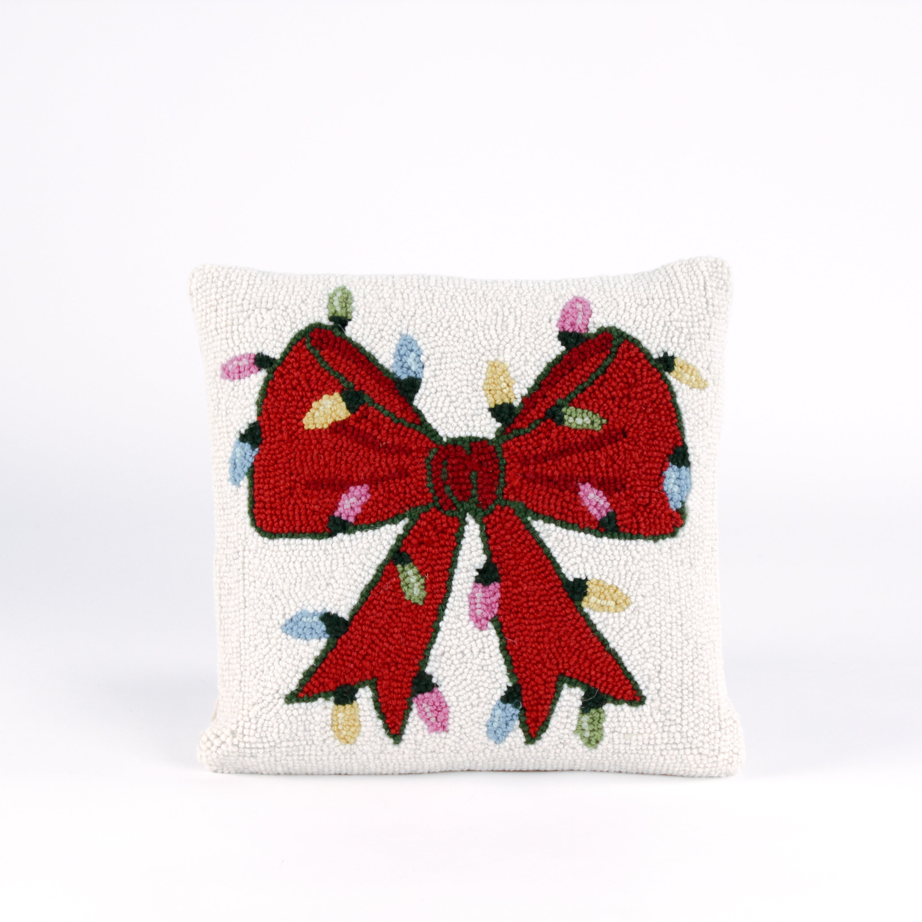 Hooked wool Christmas pillow featuring a square white design with a large red Christmas bow wrapped in multicolored holiday string lights.