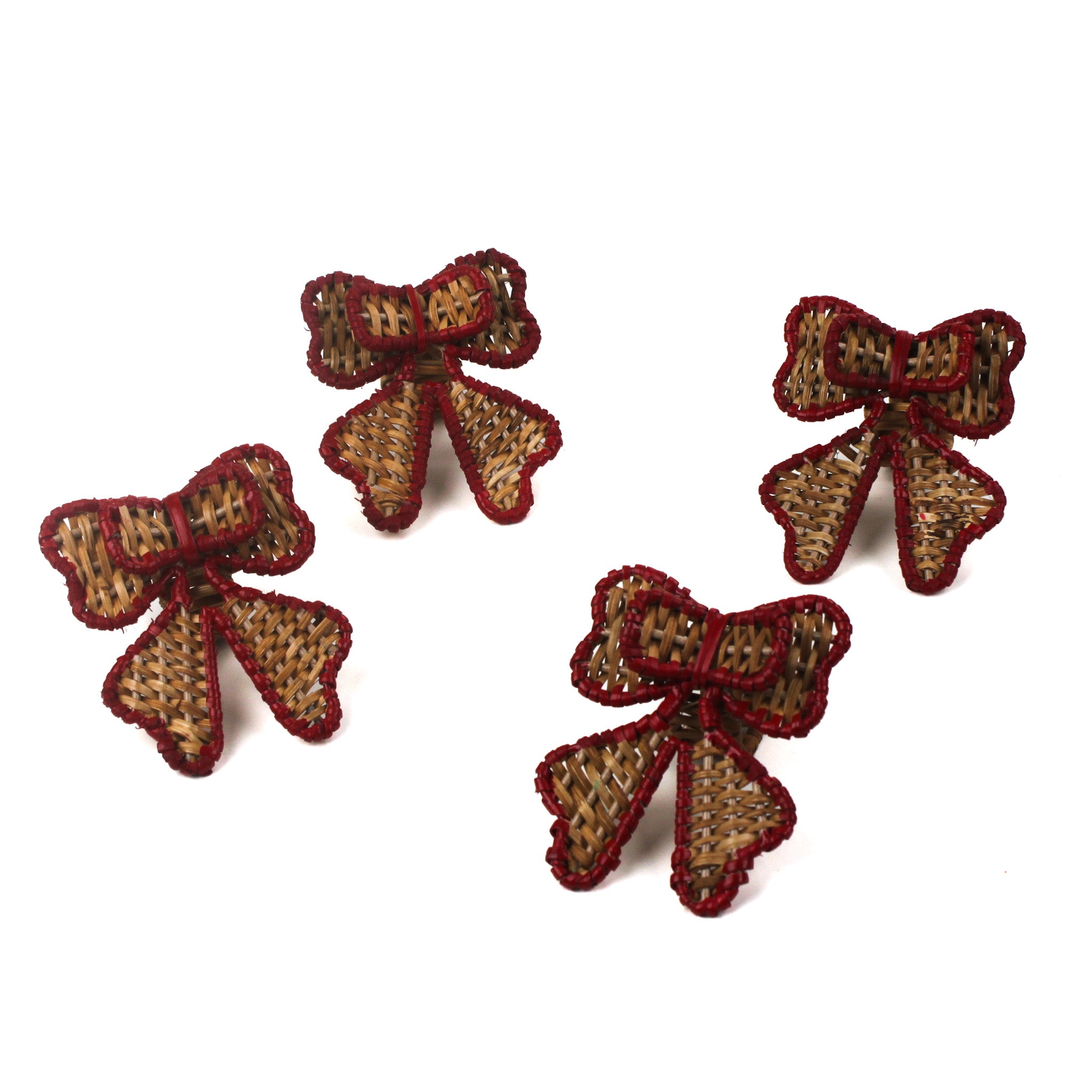 Set of four red-trimmed rattan bow napkin rings arranged on a white background.