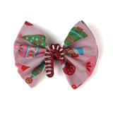 a red candy cane christmas napkin ring filled with a pink christmas napkin with ornament motifs against a white background. 