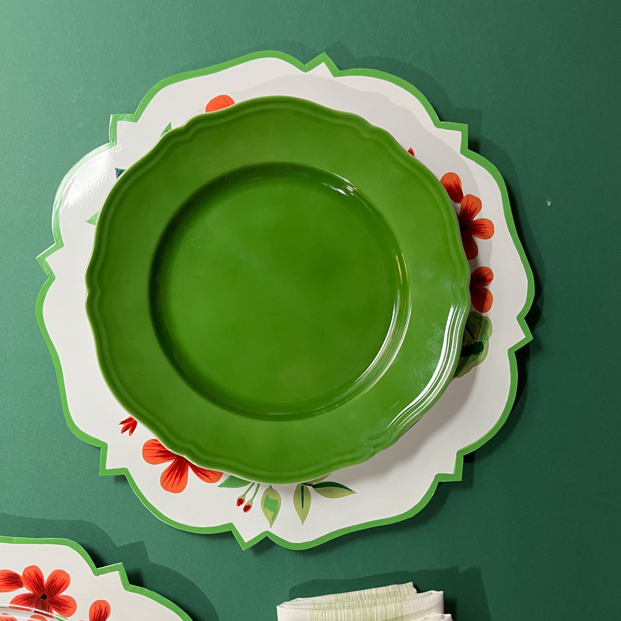 a metal geranium charger plate with a green plate resting on top