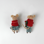 back of Two felt mouse ornaments wear festive red jackets and blue-green clothing—one holding a teddy bear and the other carrying a holiday wreath—lying flat