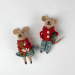 Two felt mouse ornaments wear festive red jackets and blue-green clothing—one holding a teddy bear and the other carrying a holiday wreath lying flat