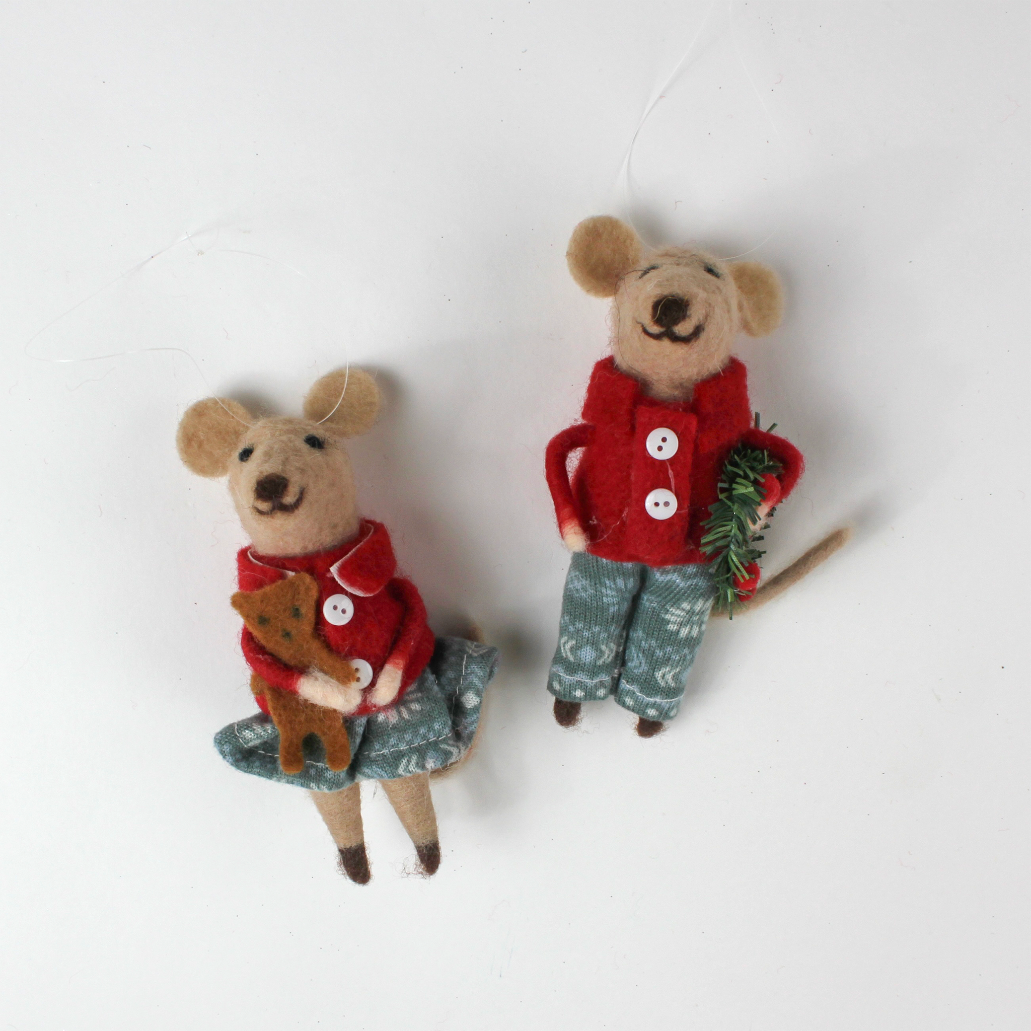 Two felt mouse ornaments wear festive red jackets and blue-green clothing—one holding a teddy bear and the other carrying a holiday wreath lying flat