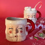 Ceramic Christmas santa mug with a jolly santa face design with red cheeks and a red handle on a white background