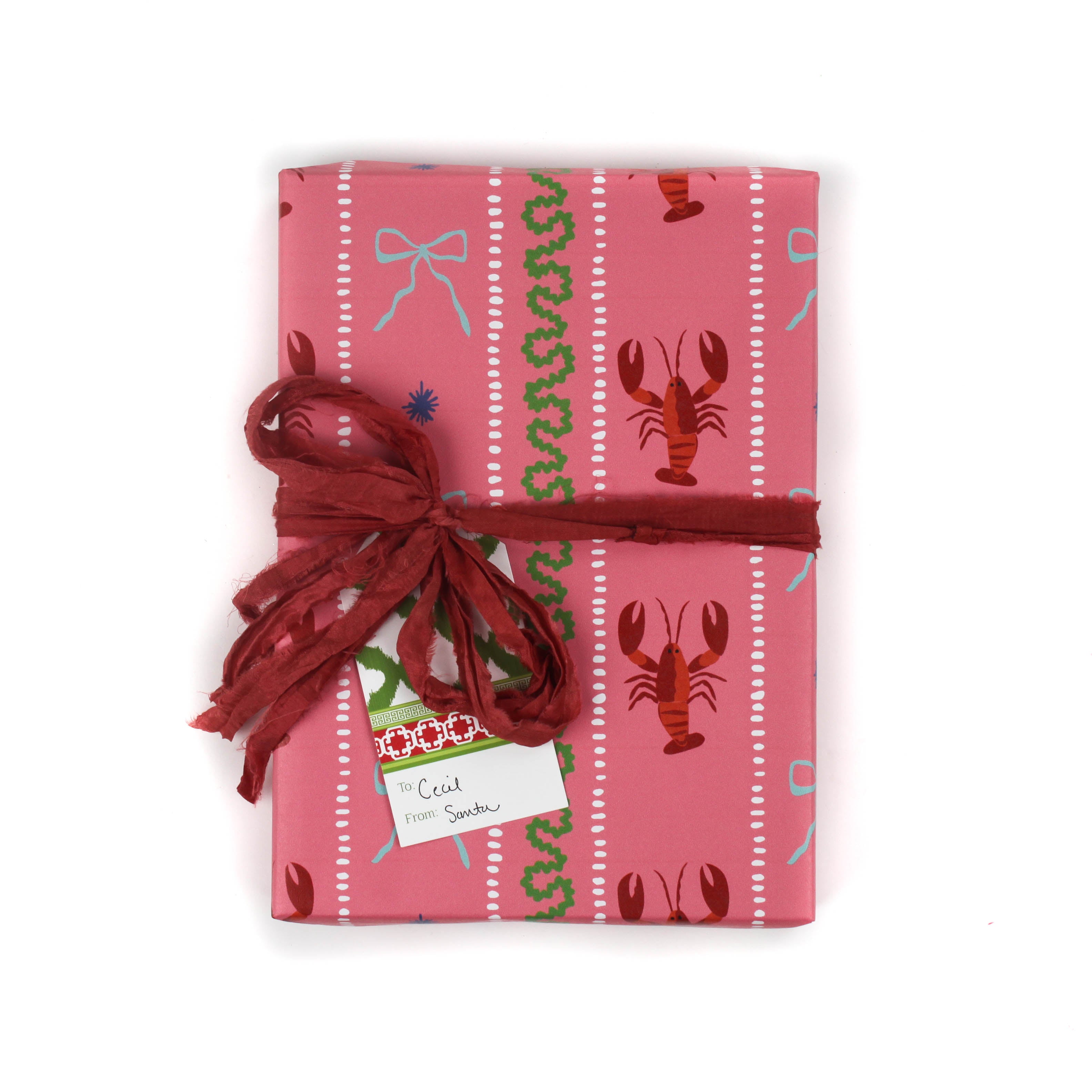 Pink wrapping paper featuring a blue ribbon and orange lobster motif