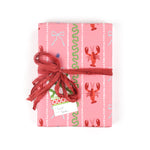 a Pink wrapping paper roll with a festive pattern featuring lobsters, bows, and decorative stripes.