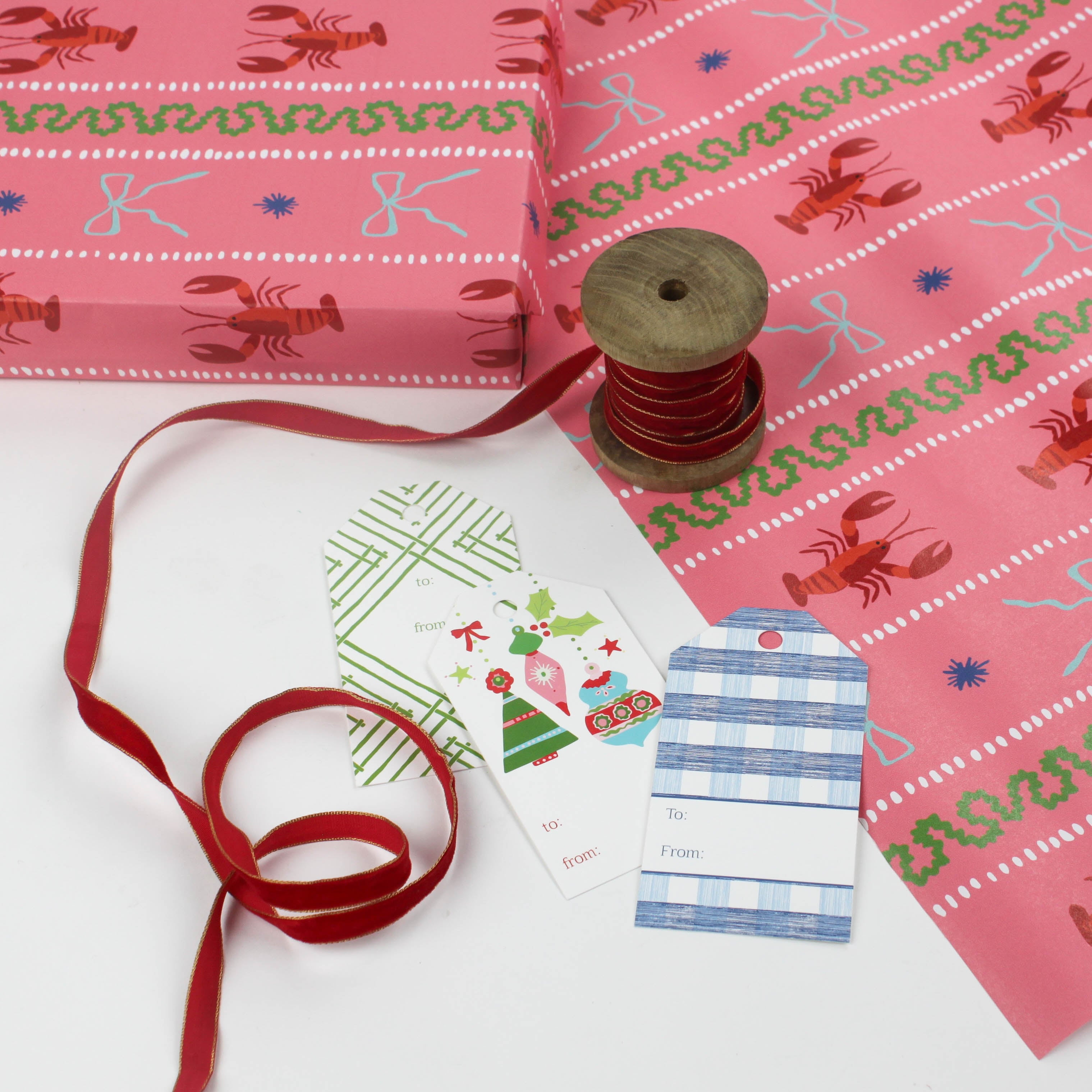 Pink wrapping paper featuring a blue ribbon and orange lobster motif