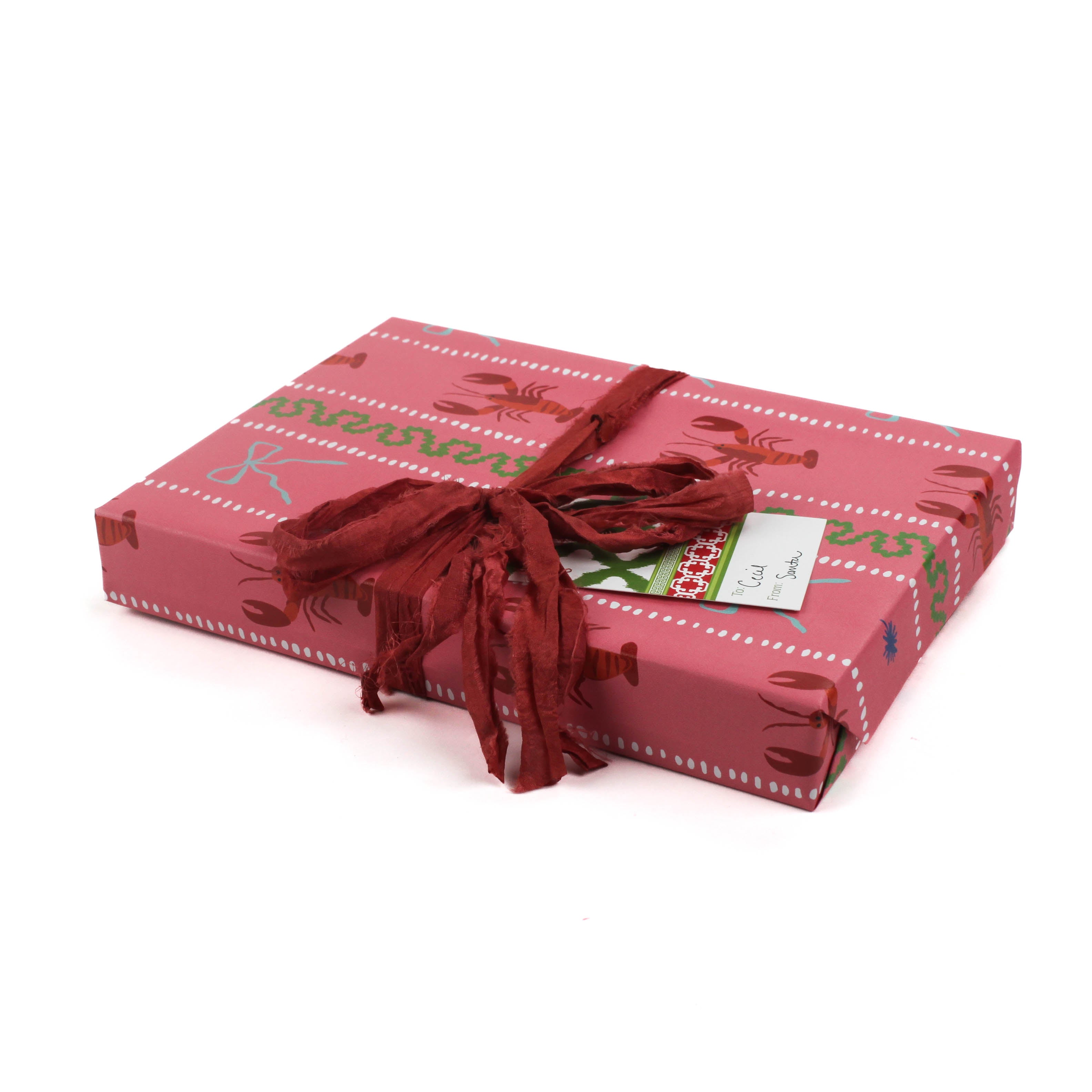 Pink wrapping paper featuring a blue ribbon and orange lobster motif
