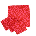 Set of red napkin cloths with playful pink squiggle pattern arranged on a white background, modern kitchen linens ideal for Christmas tea towel styling, holiday entertaining, and seasonal home décor
